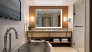 A modern bathroom with a freestanding bathtub, a large mirror, and a vanity with a sink and towel rack.