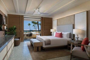 A modern hotel room with a large bed, a desk, a chair, and a view of palm trees and the ocean. - Mauna Kea Beach Hotel, Autograph Collection (Kamuela)