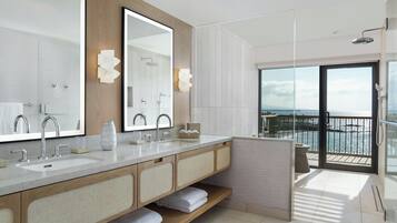 Un bagno moderno con uno specchio grande, due lavabi e una doccia. Dispone di un balcone con vista sul mare.