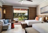 A hotel room with a balcony, a sofa, two beds, and a dining table.