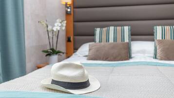 A neatly made bed with a white and blue patterned bedspread, a white hat on the bed, and striped pillows.