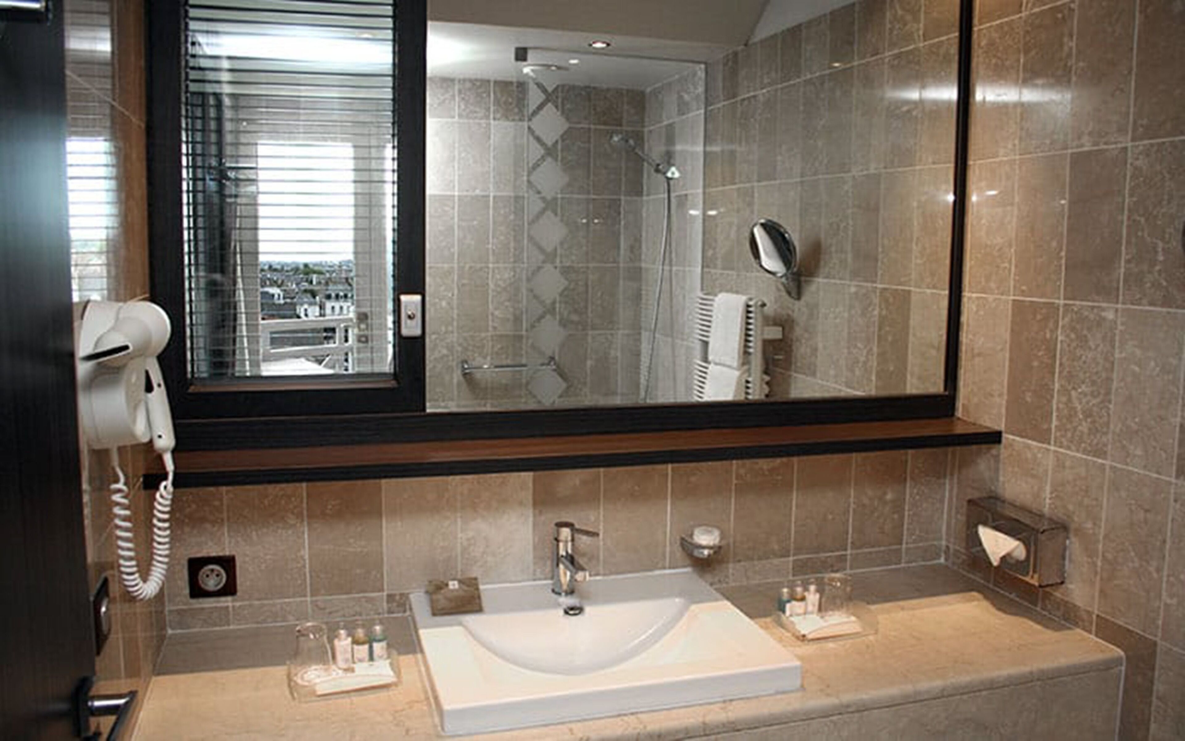 Un baño con un espejo grande, un lavabo y un secador de pelo.