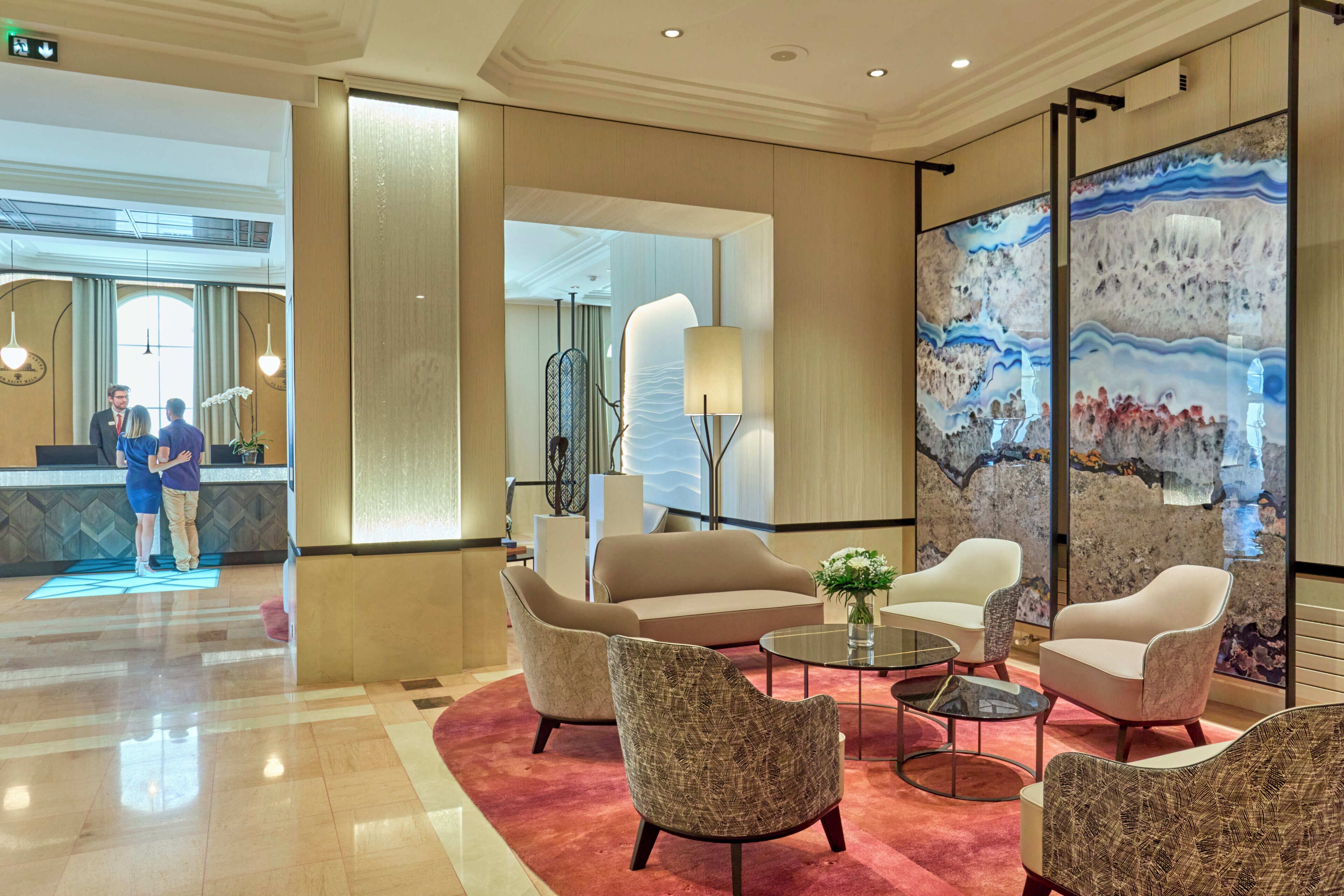 A lobby with a reception desk, seating area, and a large abstract painting.