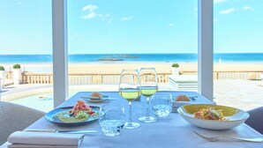 A table set for dining with a view of the beach and ocean. - Grand Hôtel des Thermes (Saint-Malo)