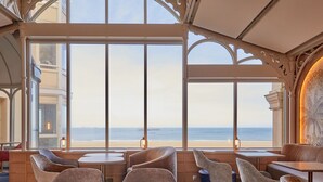A seaside restaurant with large windows, cushioned seating, and a view of the ocean. - Grand Hôtel des Thermes (Saint-Malo)