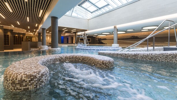 An indoor swimming pool with mosaic tiles, a skylight, and a ladder. - Grand Hôtel des Thermes (Saint-Malo)
