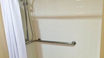 Un espacio de ducha con una barra de apoyo, una cortina blanca y un pequeño banco.