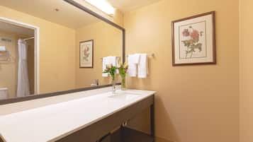 A bathroom with a large mirror, a sink, and a framed floral artwork on the wall.