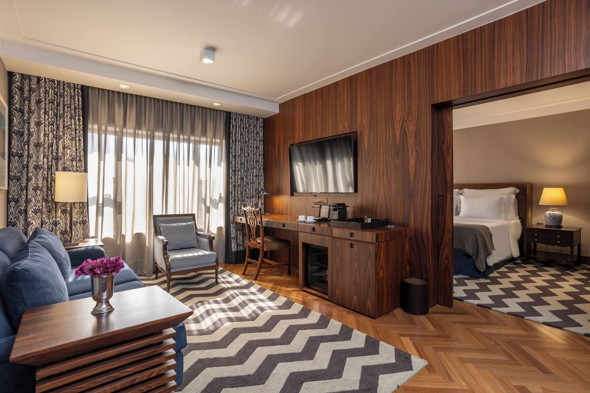 Een moderne hotelkamer met een sofa, een eethoek, een televisie en een bed.