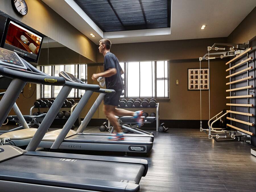 A gym with treadmills, weights, and a wall-mounted TV.
