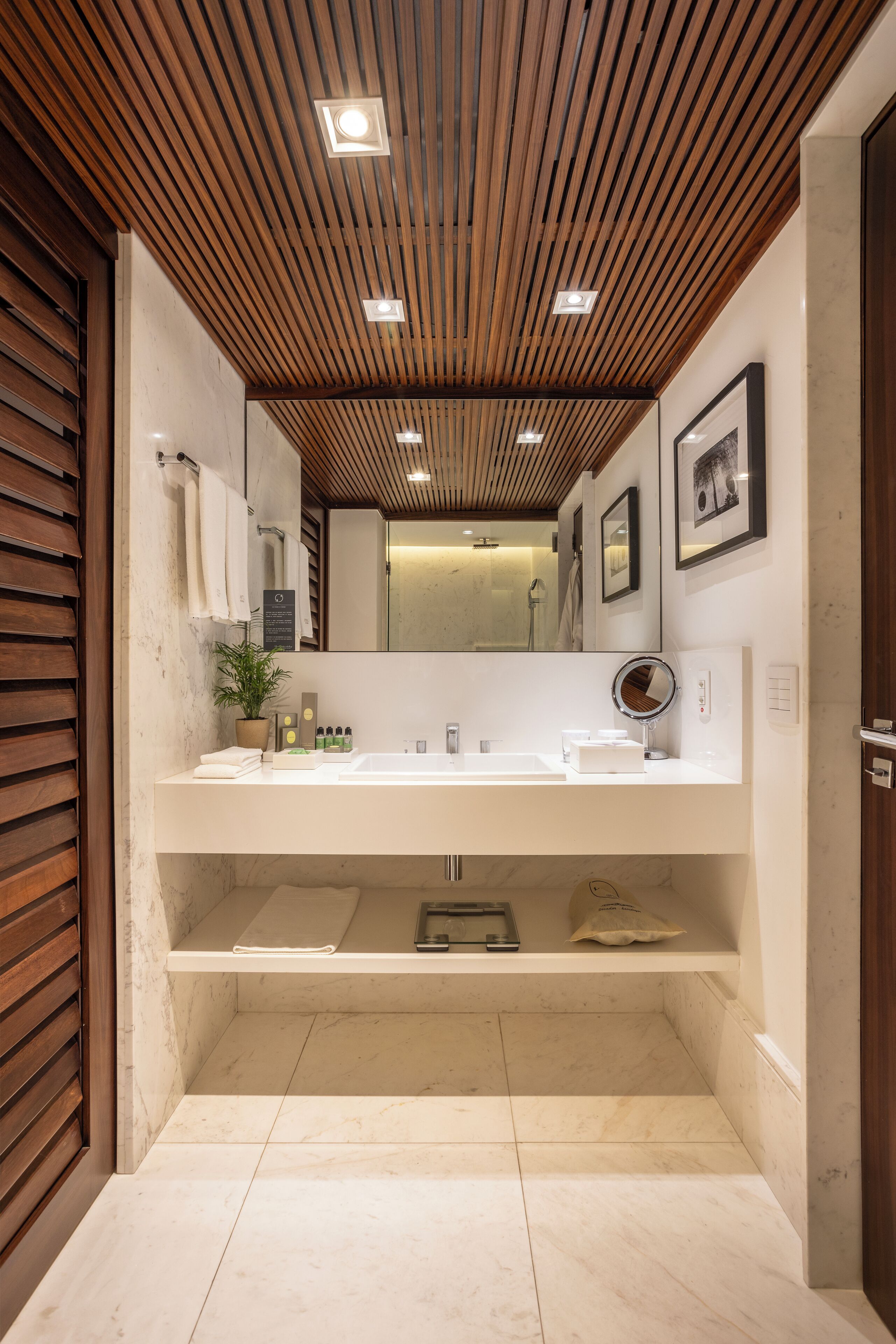 A modern bathroom with a wooden ceiling, white vanity, and a large mirror.