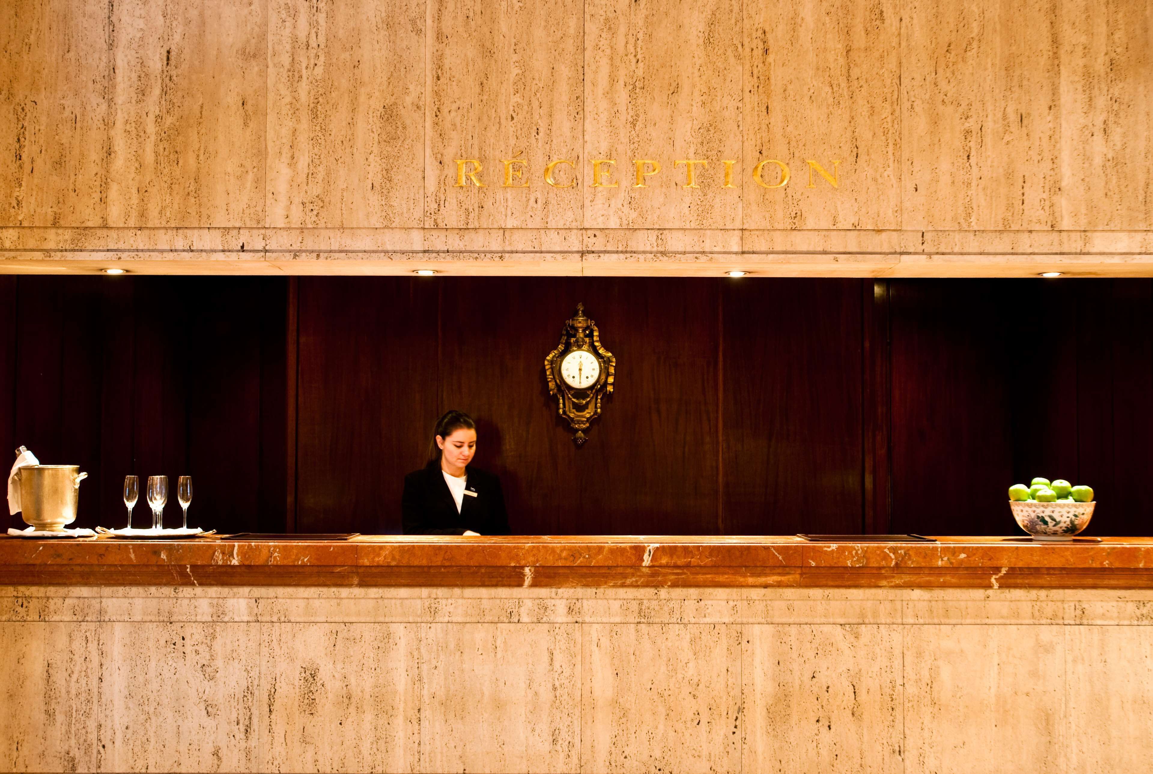 A reception area with a wooden reception desk, a clock, and a bowl of fruit.