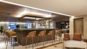 Uma área de bar moderna com banquetas de madeira, um balcão e um sofá.