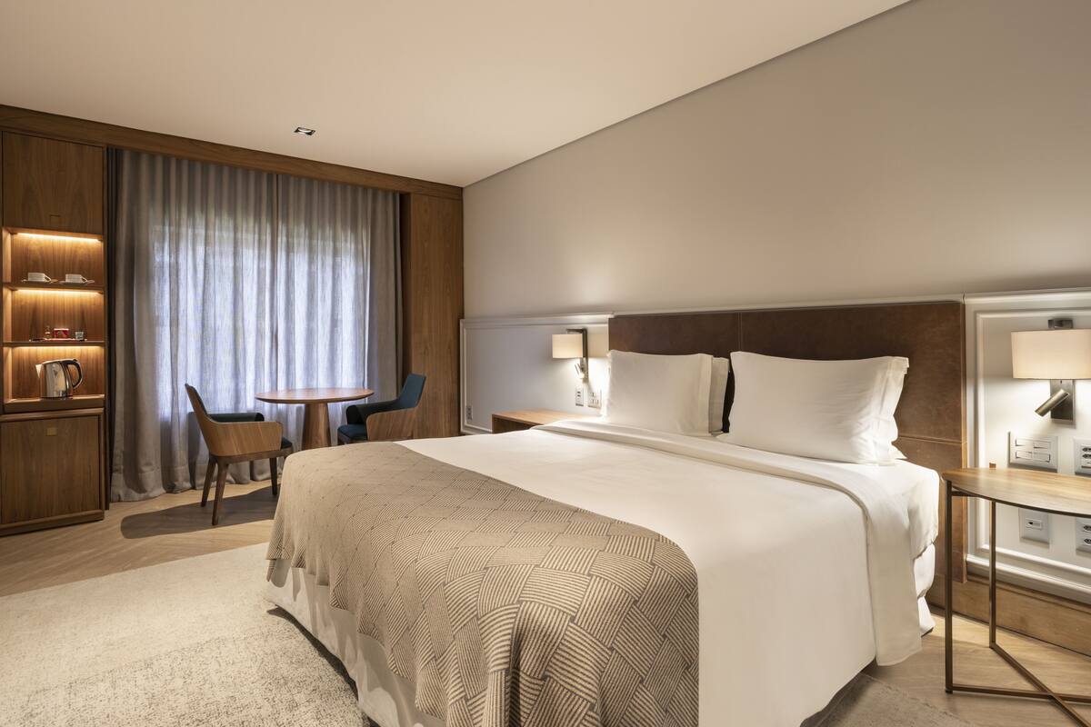 Een moderne hotelkamer met een groot bed, een bureau, een stoel en een bijzettafeltje.