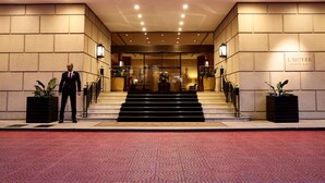 A hotel entrance with a grand staircase, a reception desk, and potted plants. - L'Hotel PortoBay São Paulo (São Paulo)