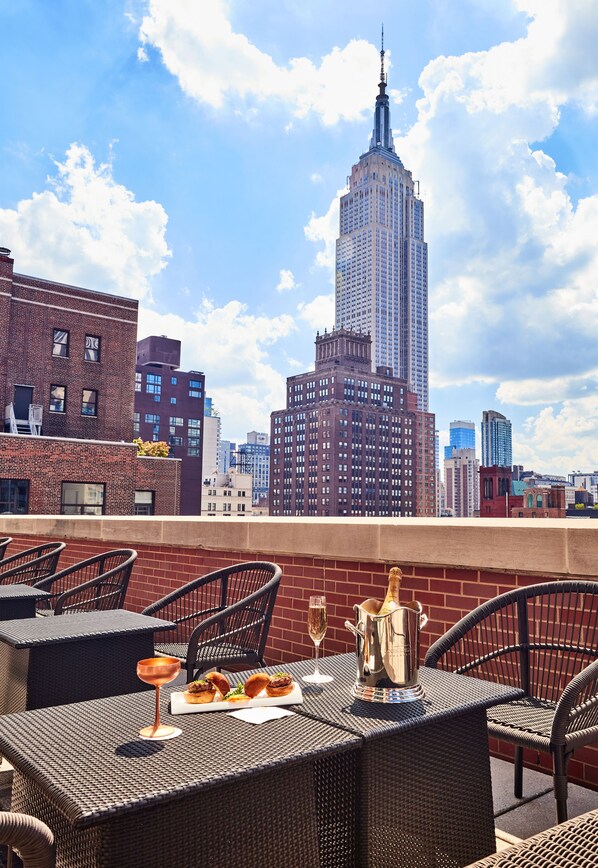 A rooftop terrace with wicker furniture, a metal pitcher, and a glass of wine. - The Kitano Hotel New York (New York)