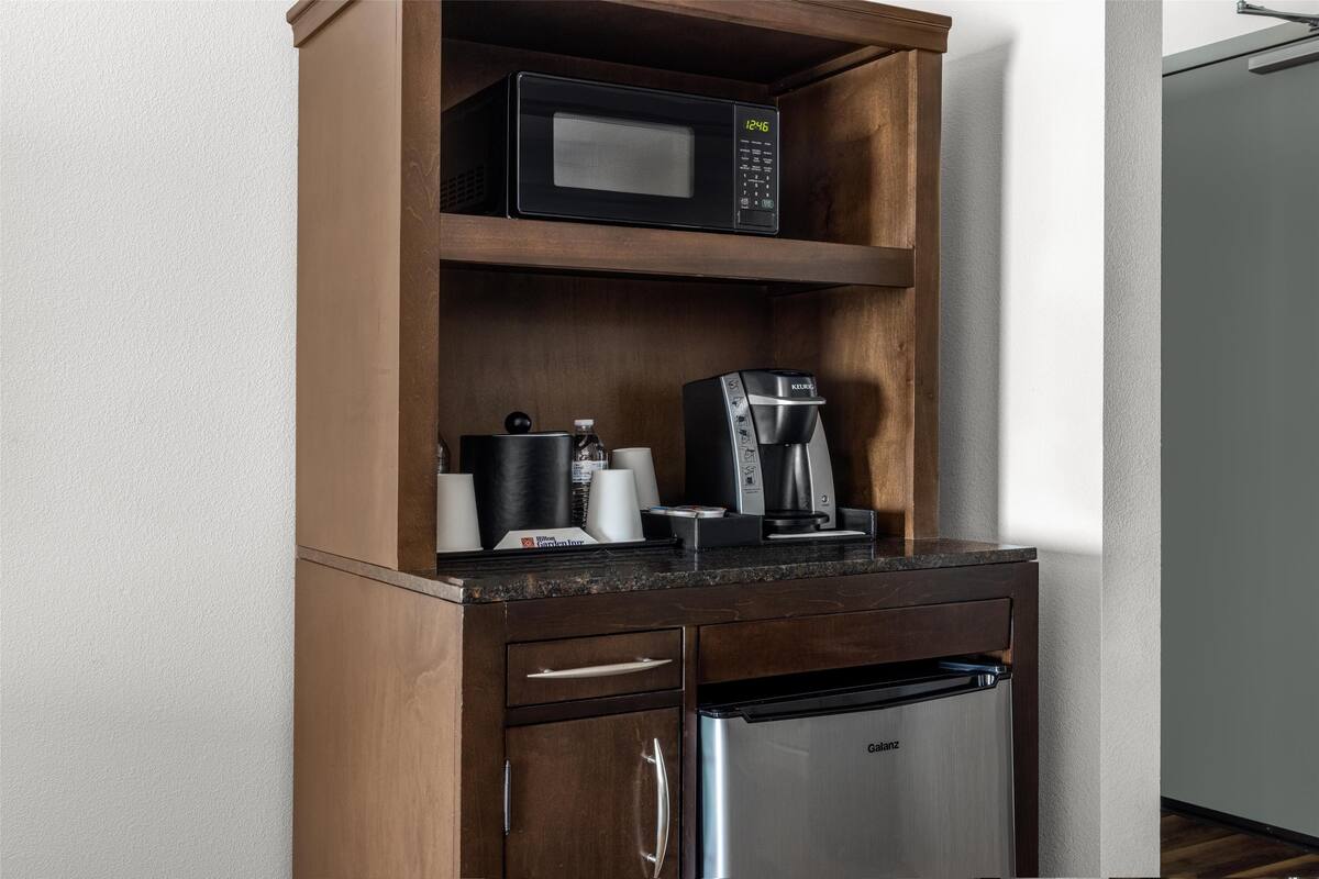 A kitchenette with a microwave, coffee maker, and a stainless steel refrigerator.