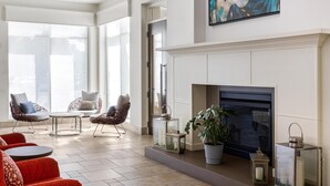 A spacious living area with a fireplace, large windows, and comfortable seating. - Hilton Garden Inn Pascagoula (Pascagoula)