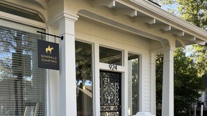 Un edificio con fachada blanca, un letrero negro con la silueta de un caballo y el número 924 en la puerta.