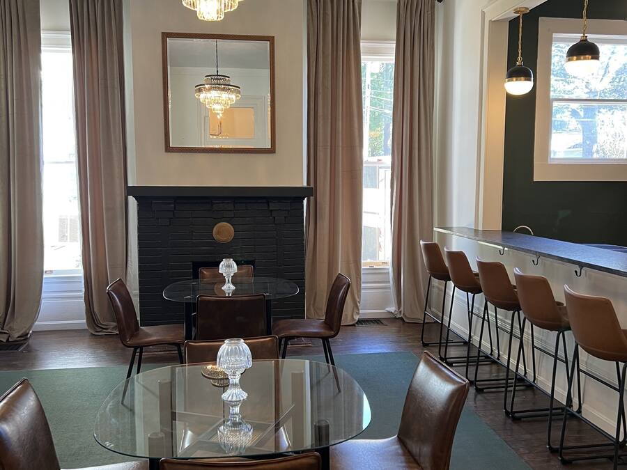 A conference room with a glass table, leather chairs, a fireplace, and a large window with curtains.