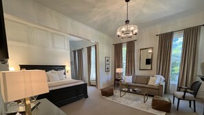 Una habitación de hotel con una cama grande, un sofá, una mesa de centro y una televisión.
