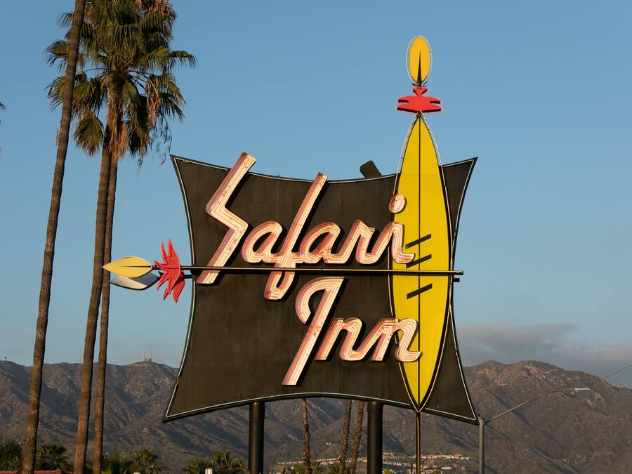 A sign for Safari Inn with a stylized safari theme, including a yellow boat and arrows.