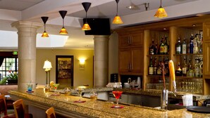 Un espace bar doté de comptoirs en granit, de tabourets de bar et d’une variété de bouteilles d’alcool.