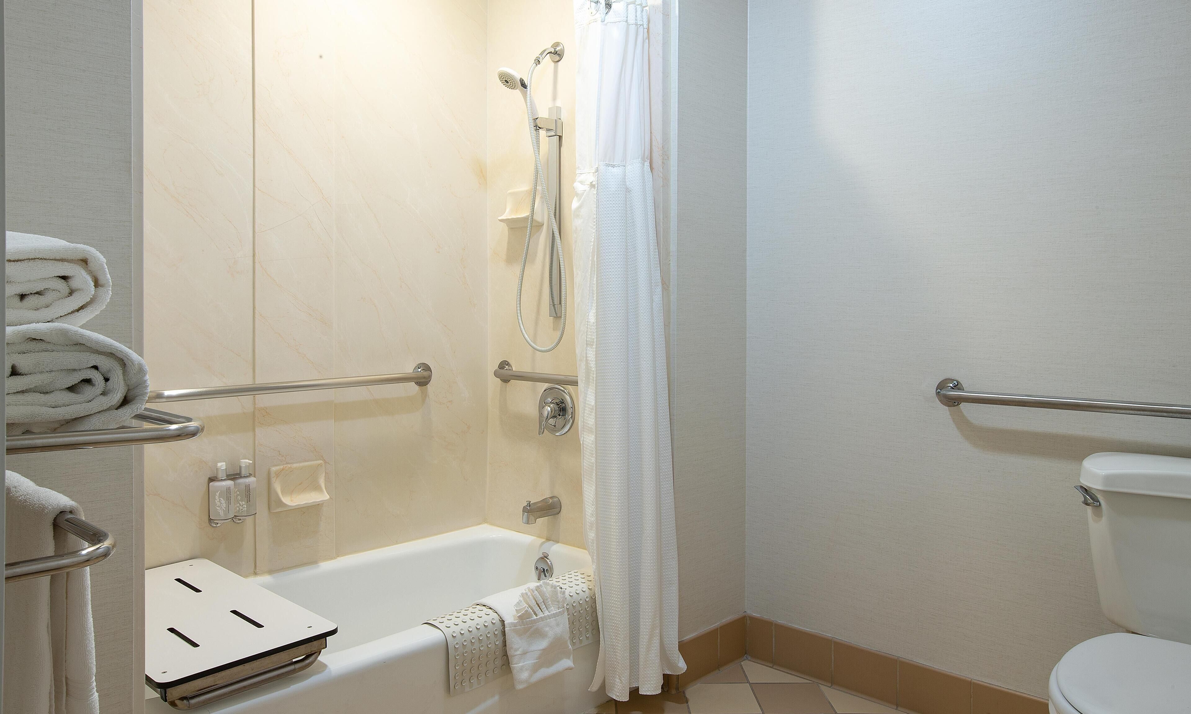 A bathroom with a bathtub, toilet, and shower area.