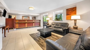 A modern living room with a leather sofa, a coffee table, and a TV mounted on the wall. - Days Inn by Wyndham Hoover Birmingham (Birmingham)