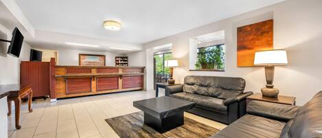 A modern living room with a leather sofa, a coffee table, and a TV mounted on the wall.
