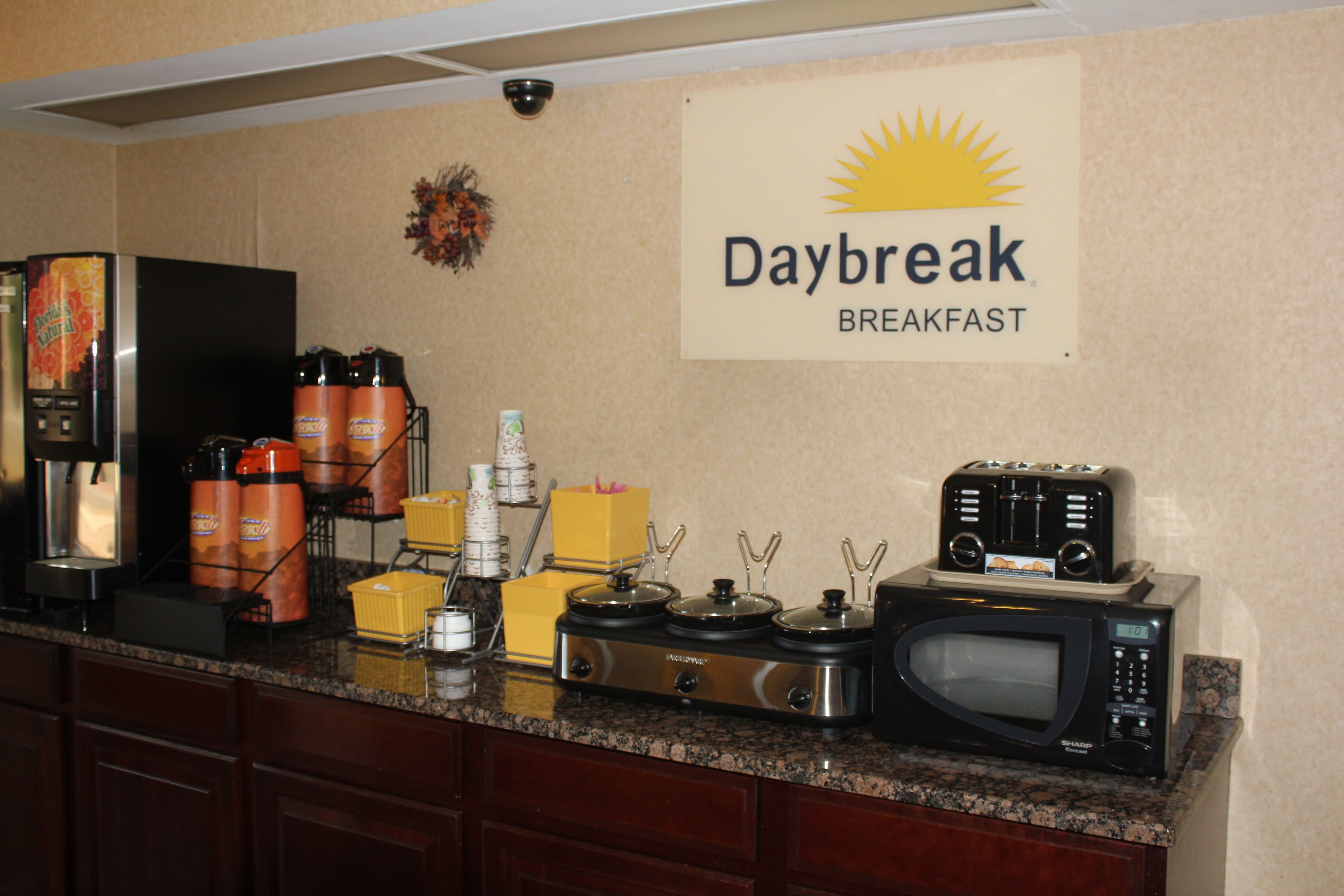 Una cocina con cafetera, microondas y un letrero que dice "Daybreak Breakfast".