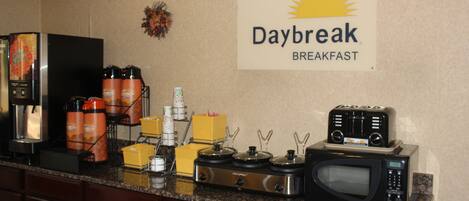 Una cocina con cafetera, microondas y un letrero que dice "Daybreak Breakfast".