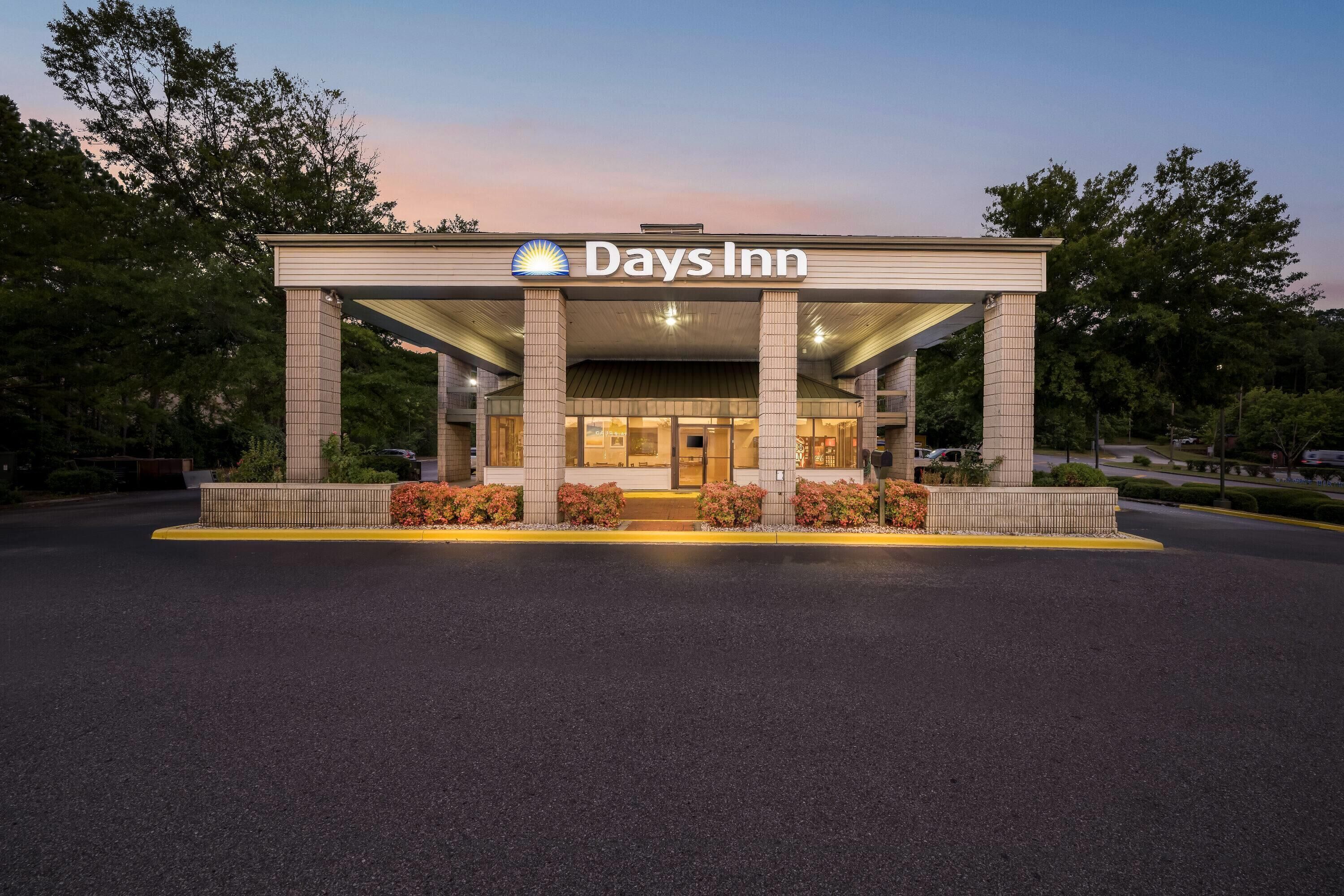 A Days Inn with a covered entrance, columns, and a landscaped area with shrubs.