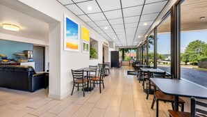 A spacious indoor area with multiple tables and chairs, a sofa, and a kitchen area. - Days Inn by Wyndham Hoover Birmingham (Birmingham)