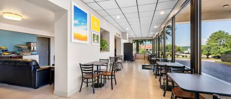 Un espacio interior amplio con varias mesas y sillas, un sofá y una zona de cocina.