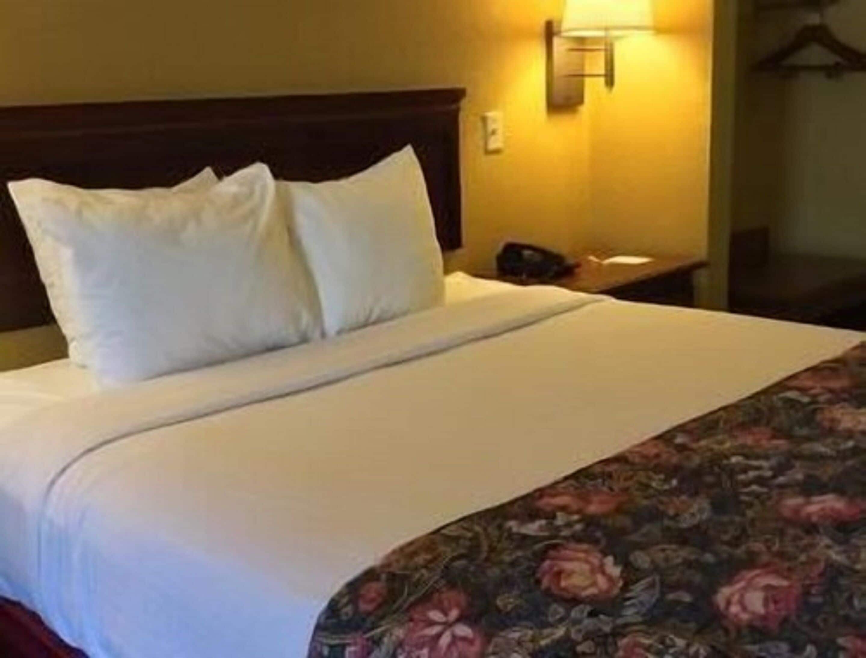 Een hotelkamer met een bed, nachtkastje en een wandlamp.