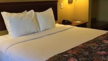 Een hotelkamer met een bed, nachtkastje en een wandlamp.