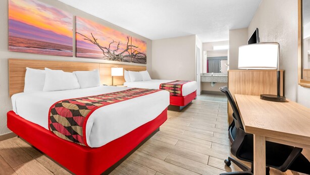 A hotel room with a large bed, a desk, and a chair. There are two paintings on the wall and a mirror. - Days Inn by Wyndham Hoover Birmingham (Birmingham)