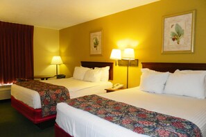 A hotel room with two beds, each with a floral bedspread, a wooden headboard, and a nightstand with a lamp. - Days Inn by Wyndham Hoover Birmingham (Birmingham)