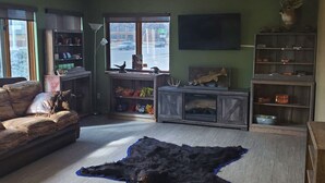 Una sala de estar con un sofá, una alfombra de piel de oso, una estantería y una cabeza de venado montada.