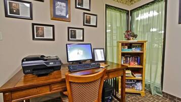 A home office with a desk, two monitors, a printer, and a bookshelf.