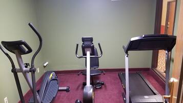 A home gym with an elliptical, a stationary bike, and a treadmill.