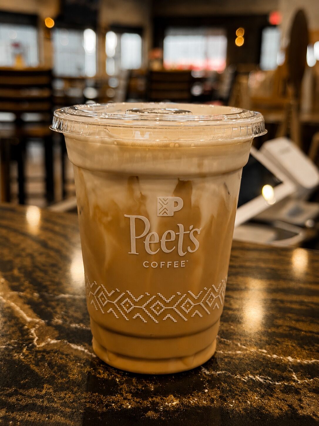 Una taza de Peet's Coffee sobre una encimera de mármol.
