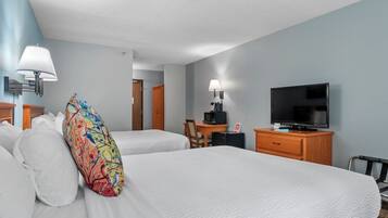 Una habitación de hotel con dos camas, un televisor, un escritorio con una silla y una lámpara.