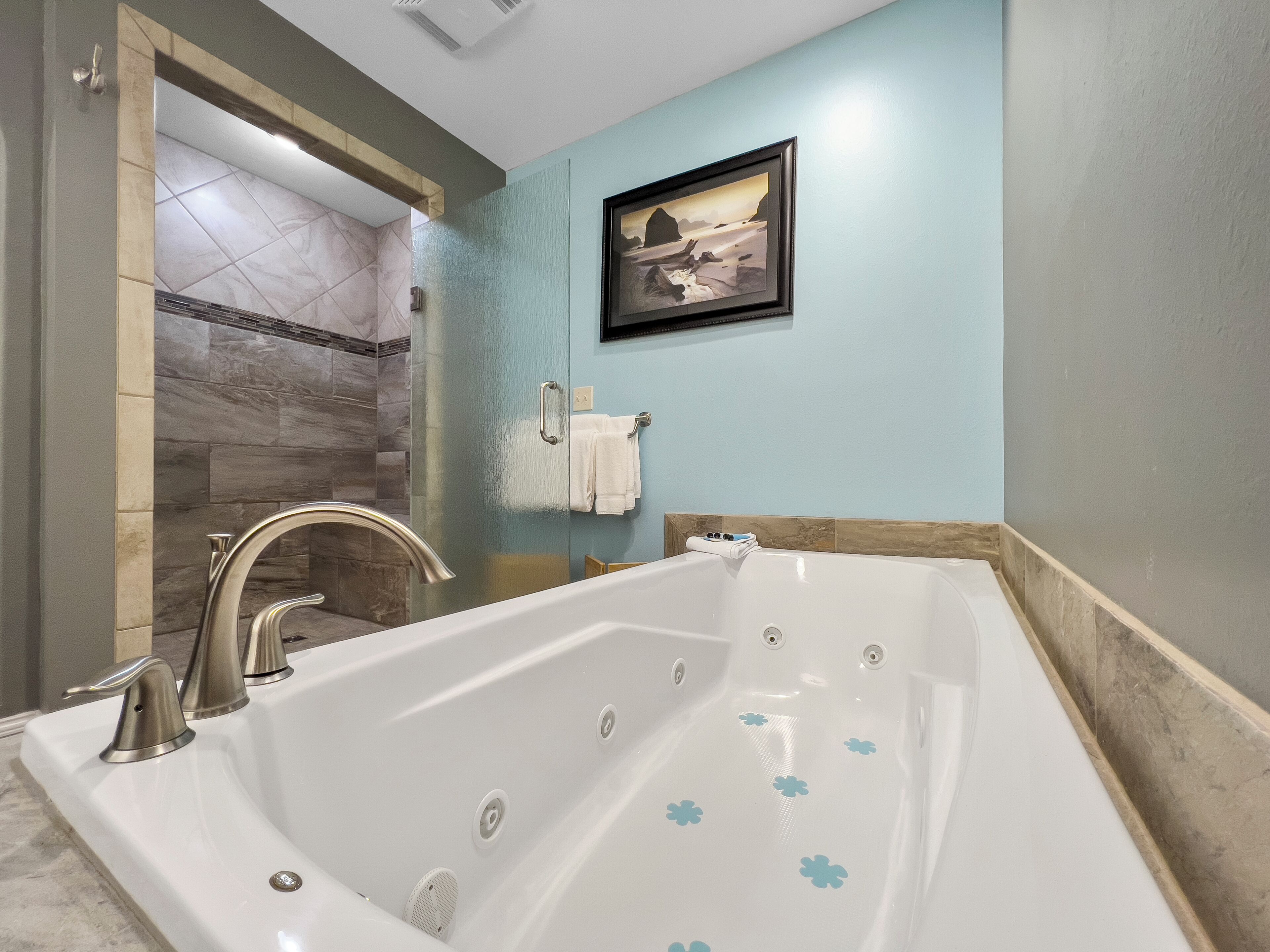Un baño moderno con una bañera grande, zona de ducha y un cuadro enmarcado en la pared.