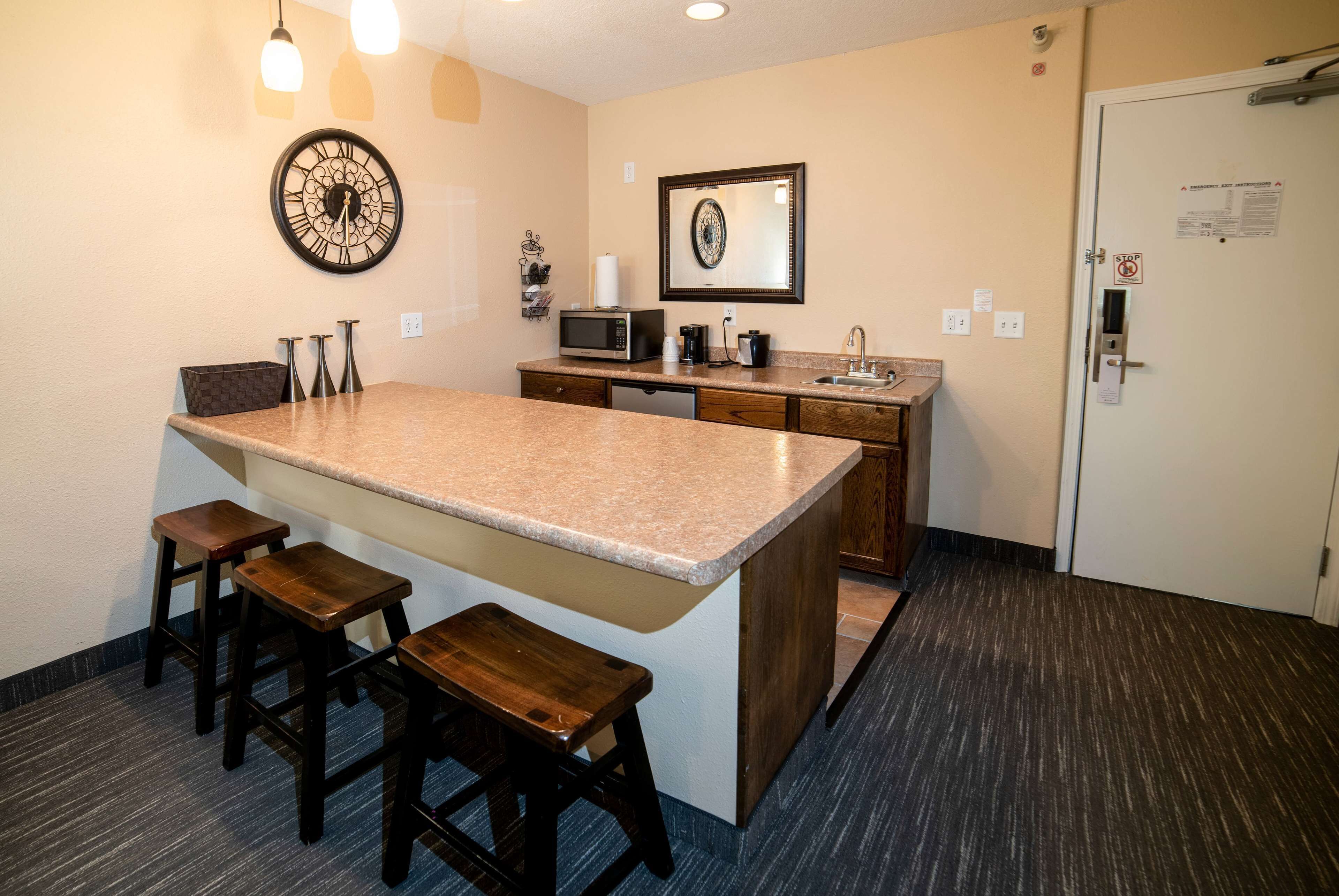 A kitchen with a large island, bar stools, a microwave, and a coffee maker.