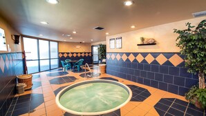 A pool area with a geometric tile pattern, a seating area with chairs, and a wall-mounted shelf with plants. - Deadwood Gulch Resort, Trademark Collection by Wyndham (Deadwood)