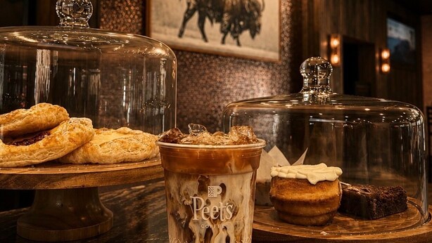 A bar area with a glass coffee cup, a pastry display, and a framed picture of a bull on the wall. - Deadwood Gulch Resort, Trademark Collection by Wyndham (Deadwood)
