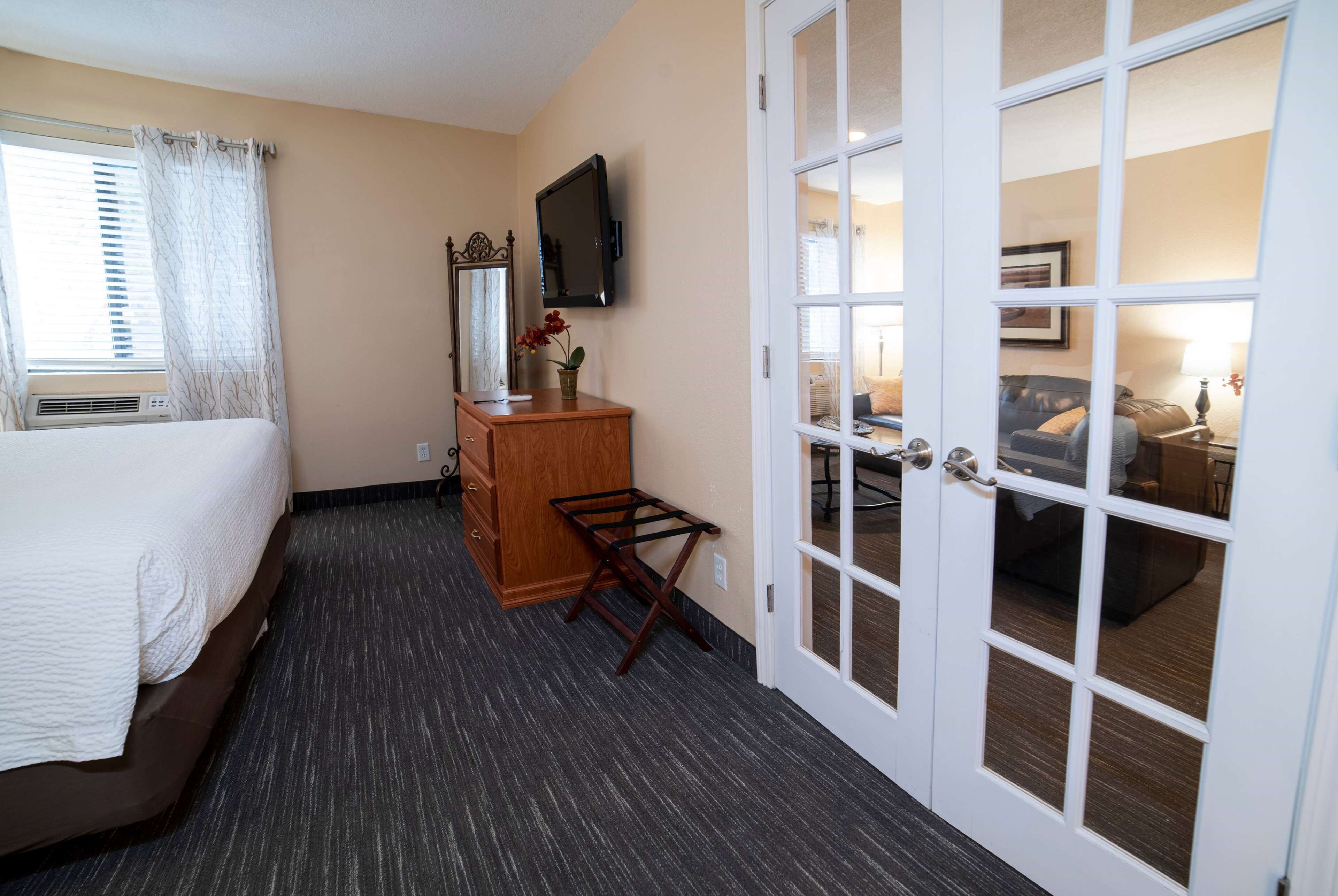 Une chambre d’hôtel comprenant un lit, une commode, une télévision et une porte donnant sur une autre pièce.