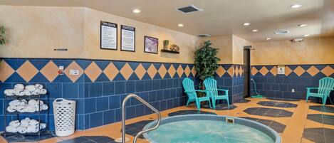 A pool area with a hot tub, chairs, and towels.